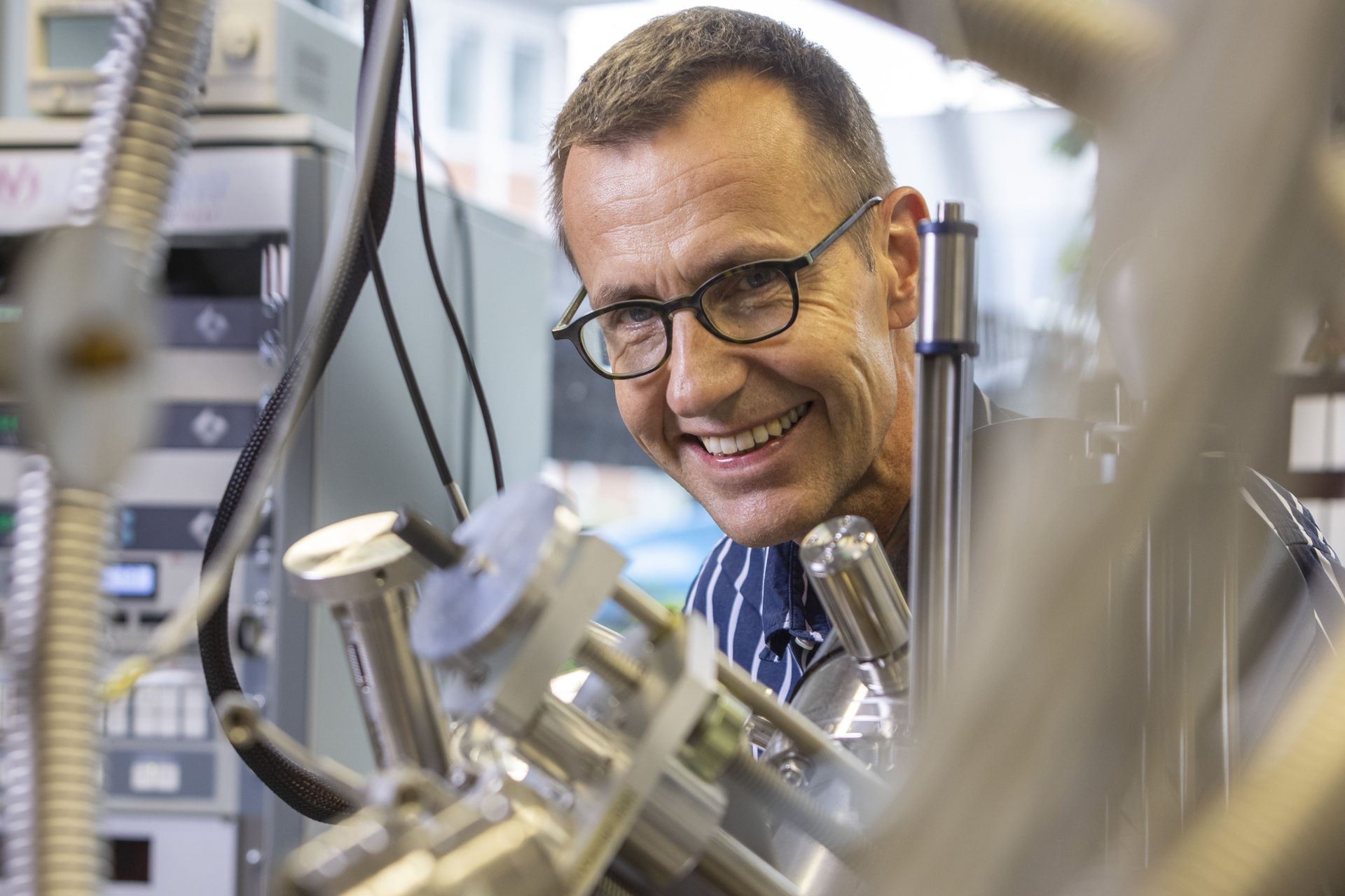 Roman Fasel, capo del settore nanotech@surfaces dell'EMPA, in piedi dietro un microscopio a effetto tunnel, nel proprio laboratorio (Foto: Gian Vaitl/EMPA)