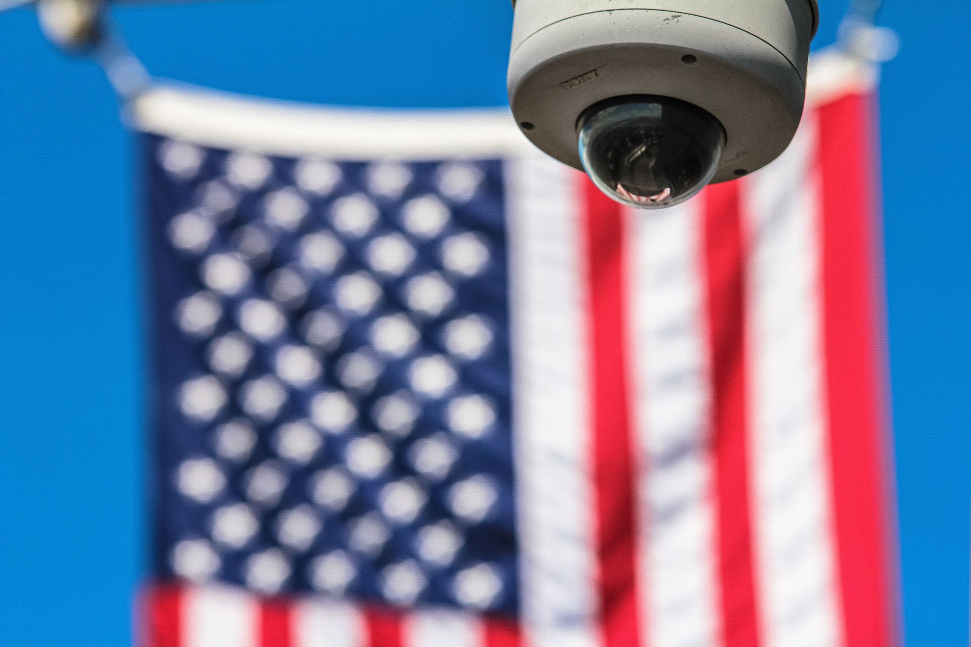 Le drapeau étoilé des États-Unis d'Amérique en arrière-plan d'une caméra de vidéosurveillance (Photo : Francesco Ungaro/Pexels)
