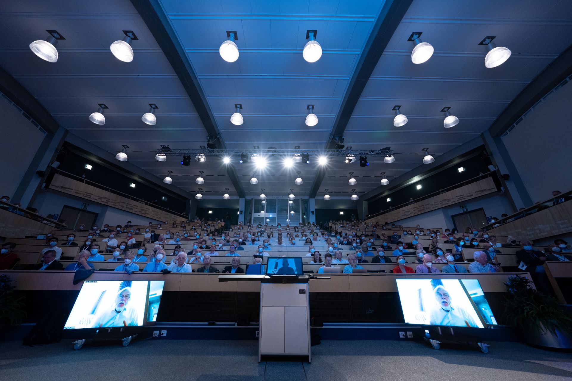 Un auditorium gremito ascolta Rolf Heuer (Deutsches Elektronen-Synchrotron, Direttore Generale del CERN dal 2009 al 2015, che dà il la al "Simposio Higgs 10" in videoconferenza con il proprio discorso
