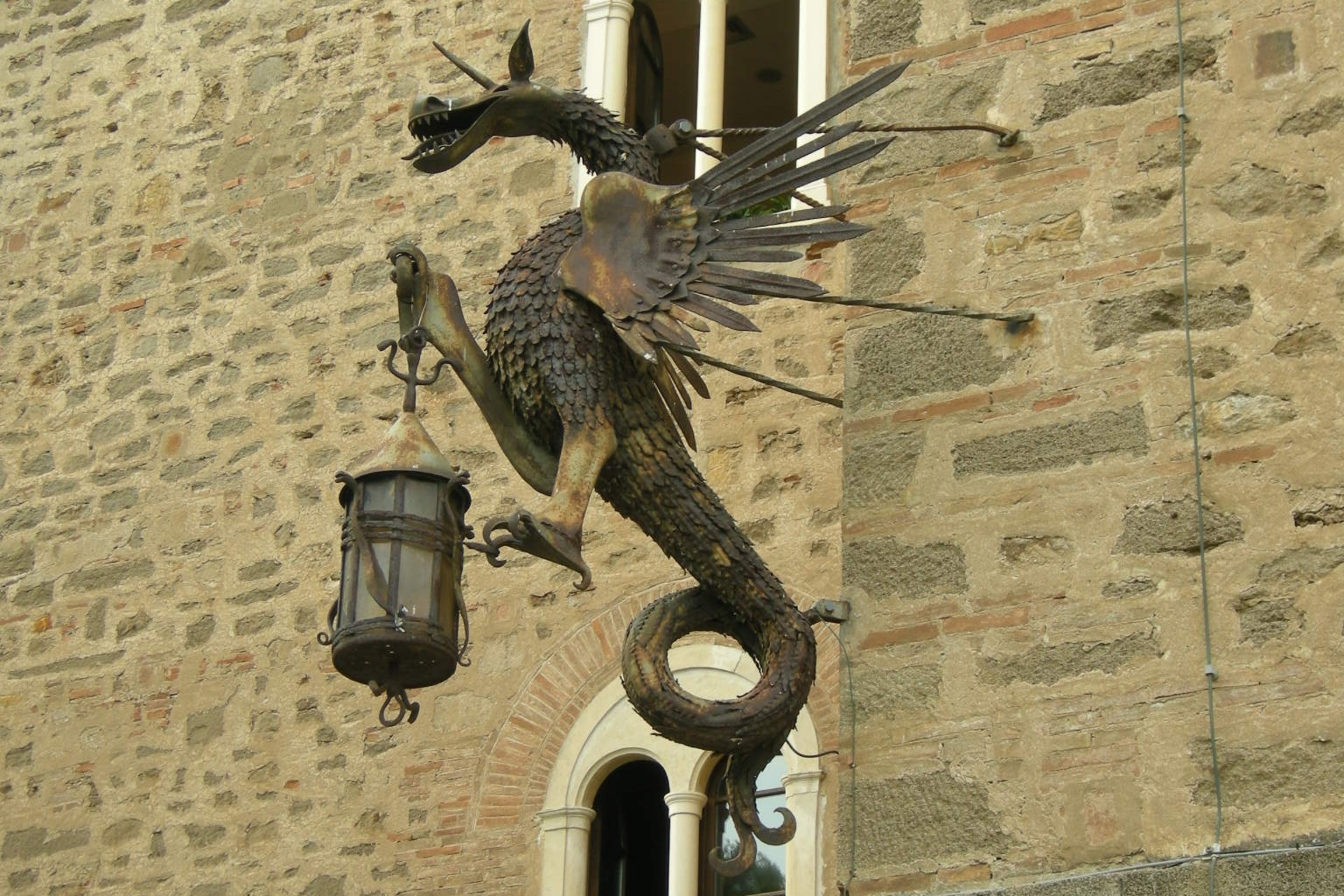 The torch-bearing dragon on the walls of Castello Pasquini in Castiglioncello di Rosignano Marittimo