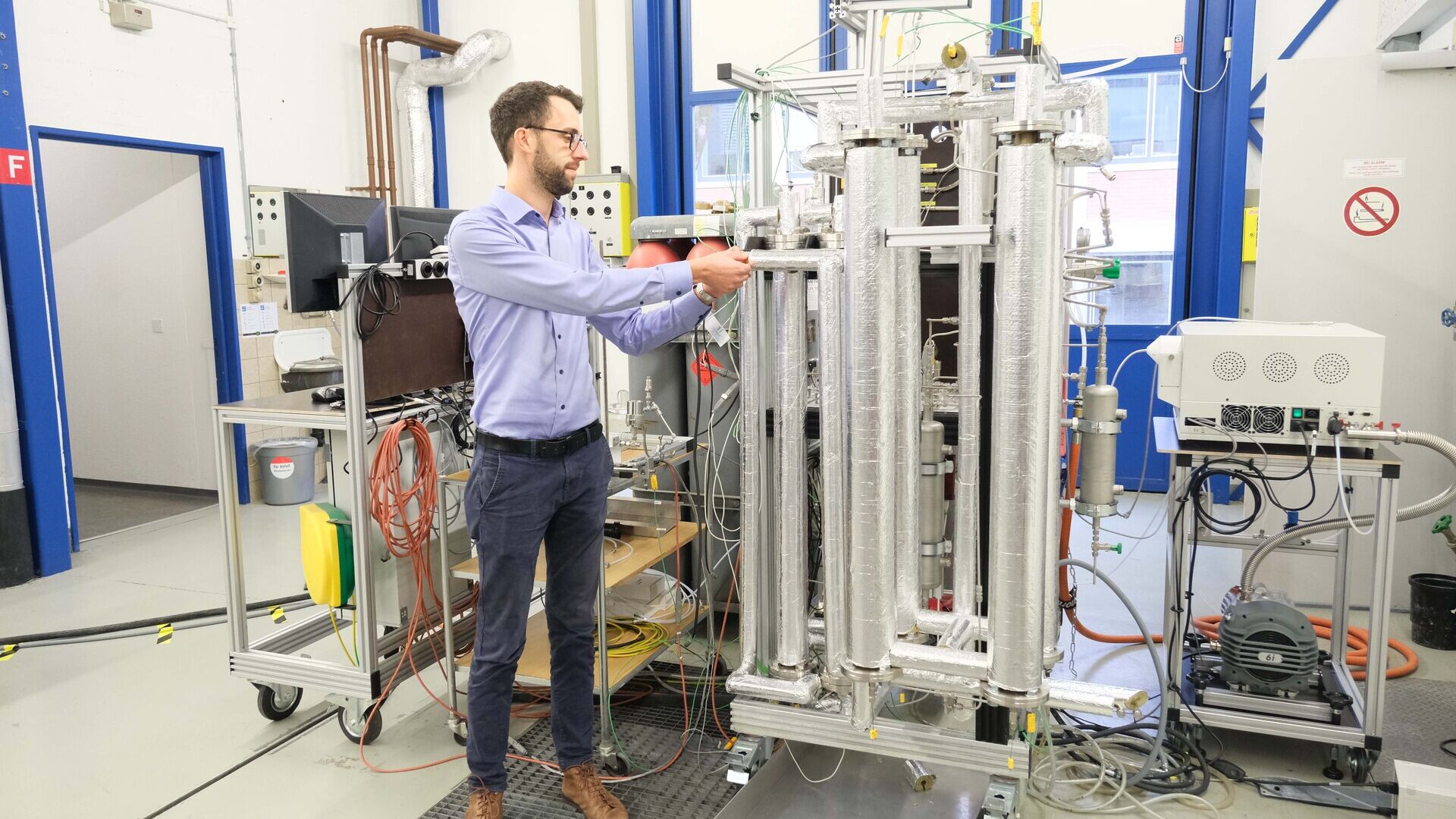 Metano sintetico: i risultati del nuovo concetto di reattore possono essere implementati per impianti su larga scala: Florian Kiefer, responsabile del progetto per la metanazione con assorbimento presso l’EMPA, accanto all'impianto di prova (Foto: EMPA)