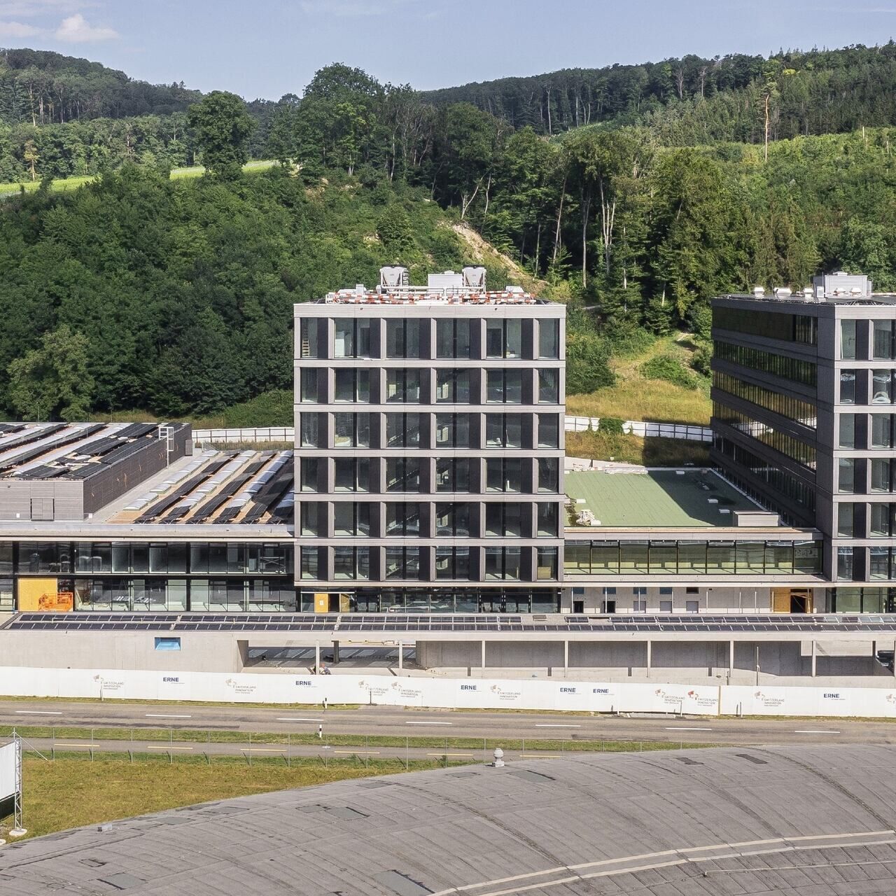 Swiss PIC: il centro di trasferimento tecnologico “Swiss PIC” si sta trasferendo nel Park InnovAARE e quindi nelle immediate vicinanze dell’Istituto Paul Scherrer: il tetto rotondo in primo piano appartiene alla Sorgente di Luce del Sincrotrone SLS, che si trova nel sito del PSI West; dietro di esso, si può vedere parte del complesso di edifici del parco tecnologico argoviese (Foto: Paul Scherrer Institute)