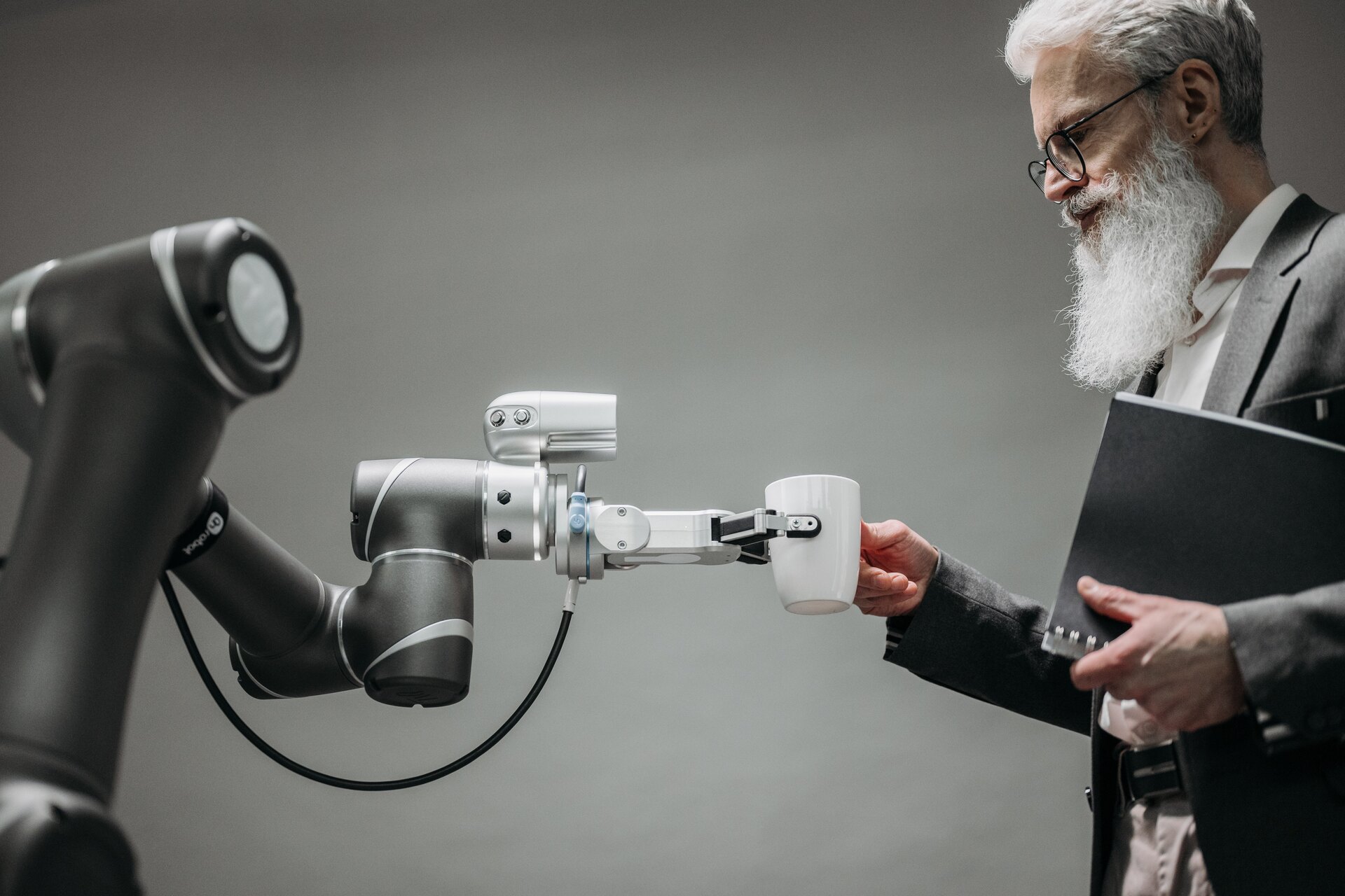 Futuro del lavoro: un uomo d'affari prende una tazza dalla mano artificiale di un robot: in futuro l'intelligenza umana e artificiale collaboreranno